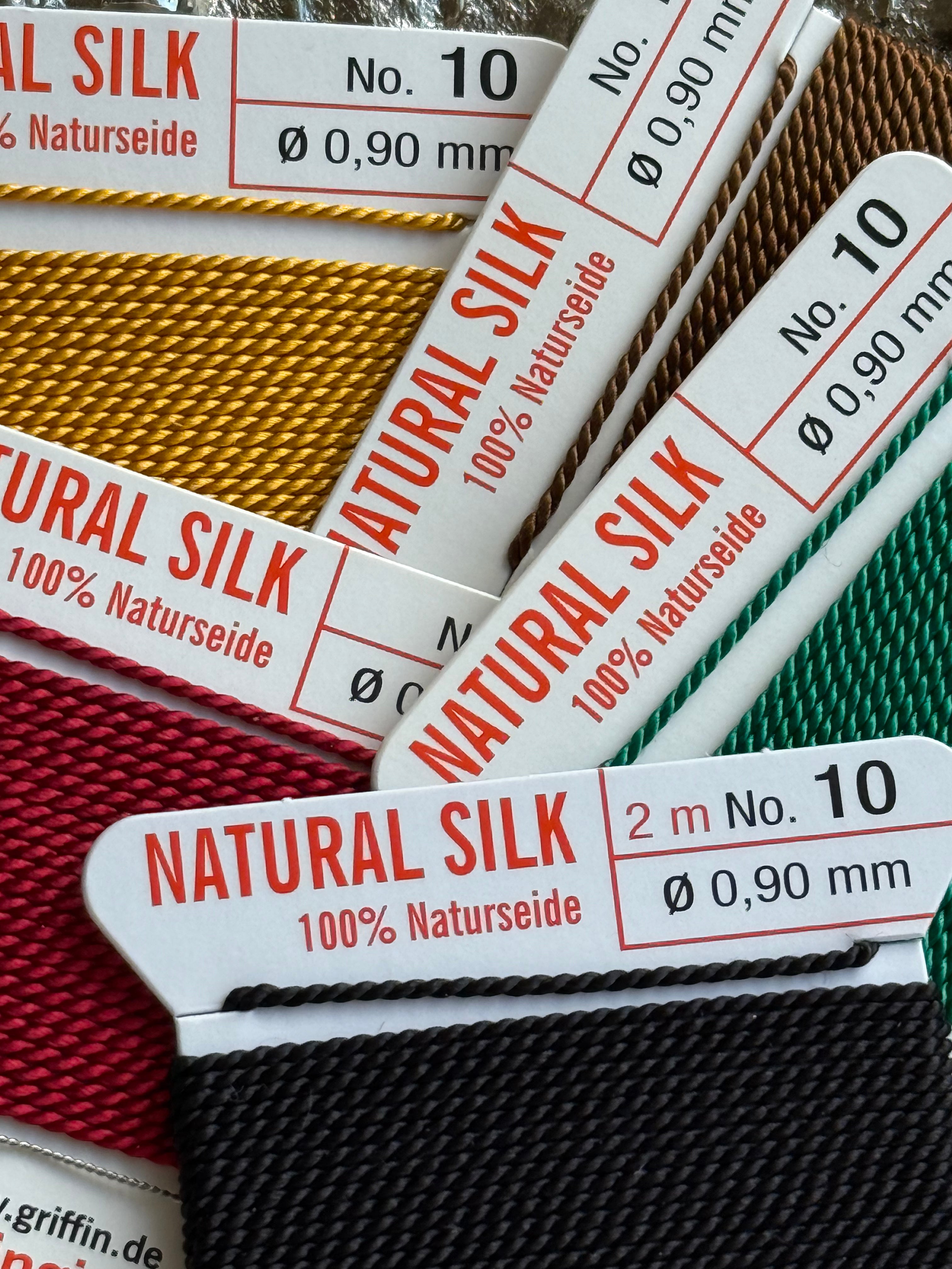 Spools of natural silk thread with labels indicating brand and specifications for silk  friendship bracelets.